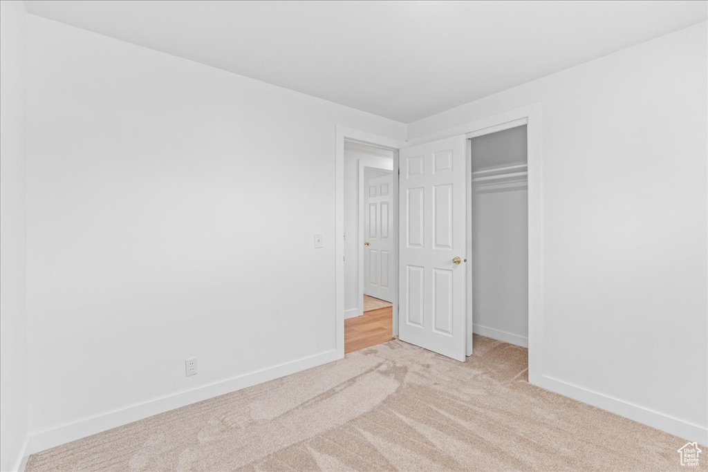 Unfurnished bedroom featuring light carpet and a closet