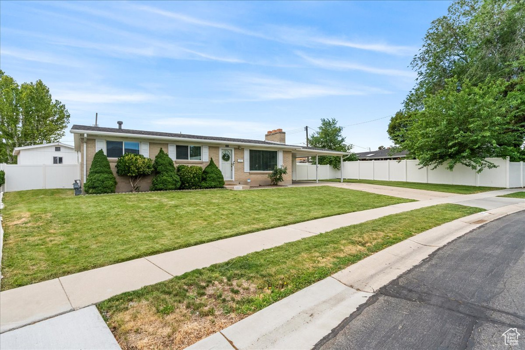 Single story home featuring driveway, an attached carport, a chimney, and brick siding