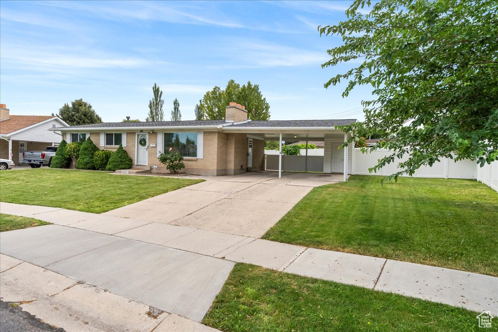 View of front of house with an attached carport, driveway, a chimney, and brick siding