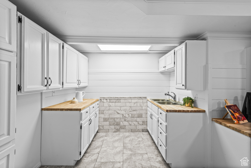 Kitchen with wood counters and white cabinetry