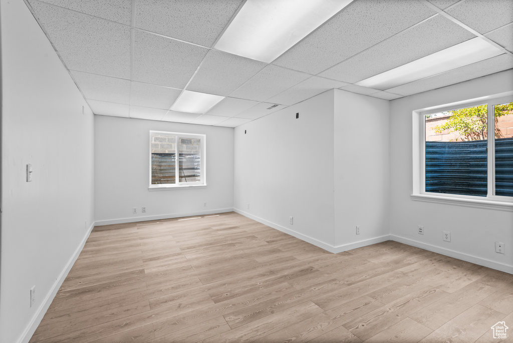 Spare room with light wood finished floors and a drop ceiling