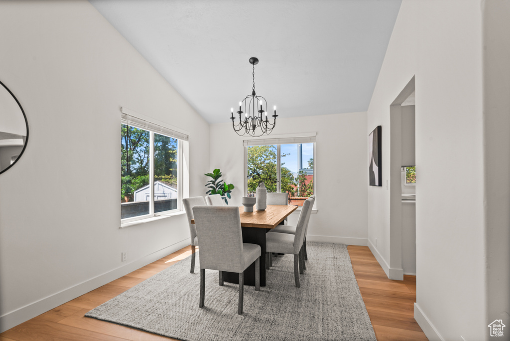 Dining area featuring a chandelier, light wood finished floors, and high vaulted ceiling