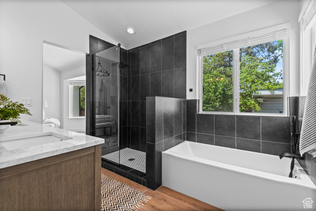 Full bath featuring a garden tub, a tile shower, lofted ceiling, healthy amount of natural light, and double vanity