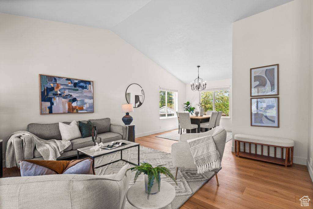 Living room with a chandelier, vaulted ceiling, and light wood finished floors