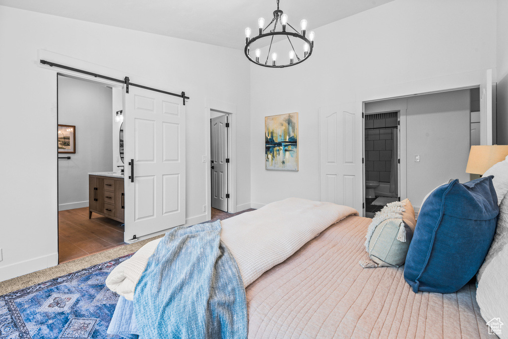 Bedroom featuring a barn door, ensuite bathroom, and a chandelier
