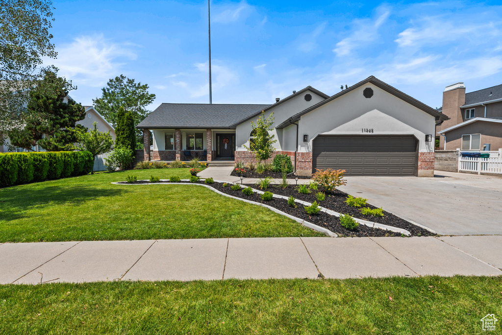 View of front of home with an attached garage, concrete driveway, a porch, and brick siding