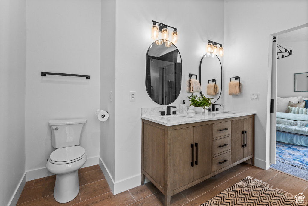 Ensuite bathroom featuring double vanity, wood finished floors, and a shower