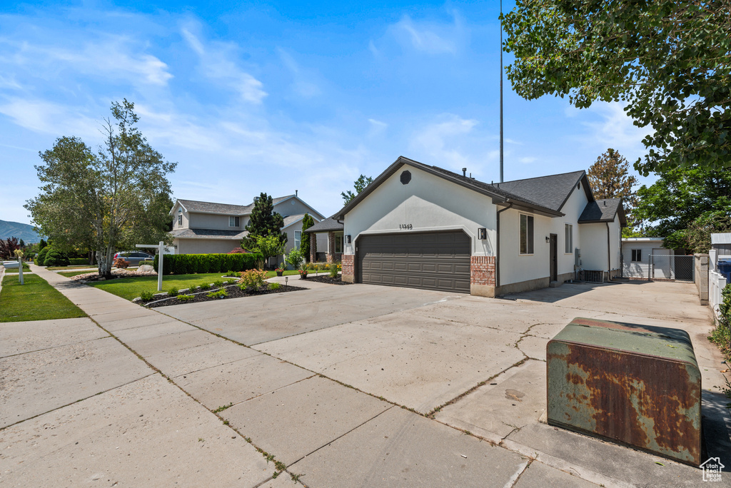View of front of home featuring a garage, stucco siding, concrete driveway, and brick siding