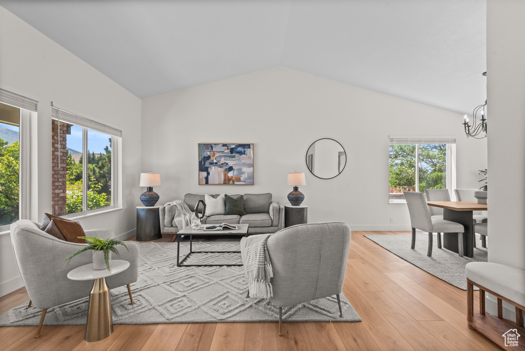 Living area featuring a chandelier, vaulted ceiling, and wood finished floors