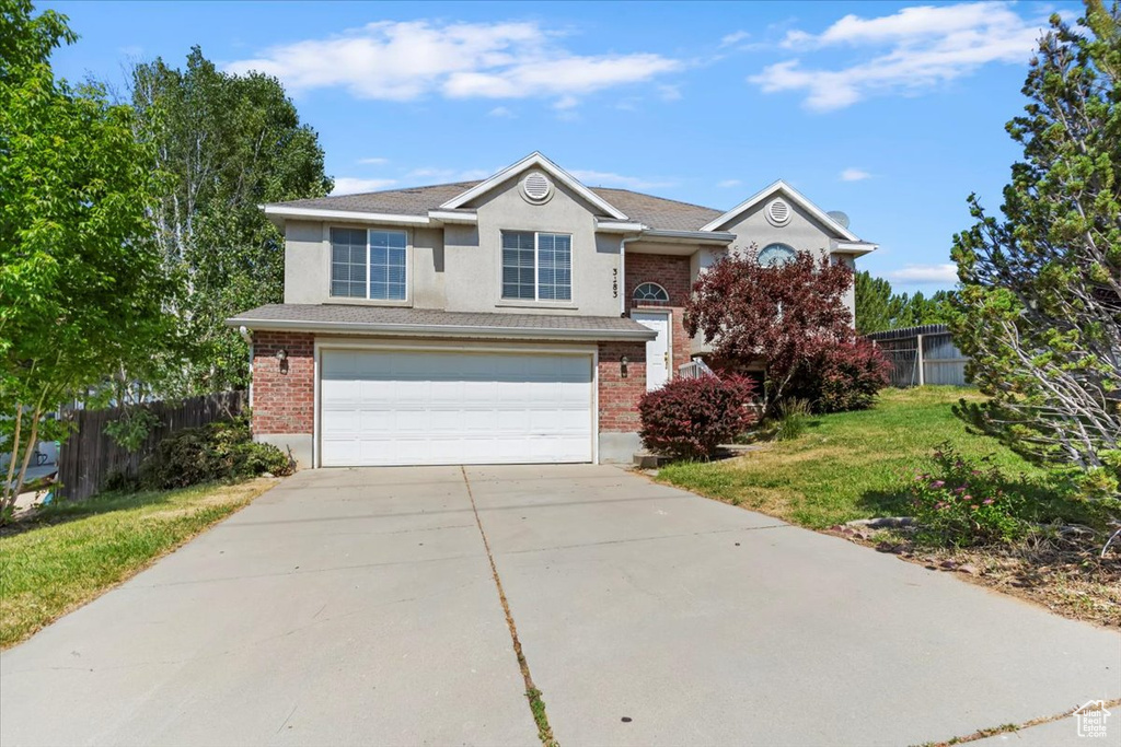 Traditional-style home featuring a garage, concrete driveway, stucco siding, and brick siding