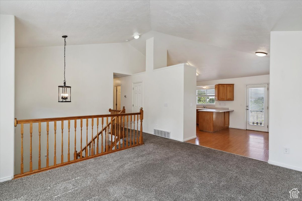 Empty room featuring carpet, lofted ceiling, and a chandelier