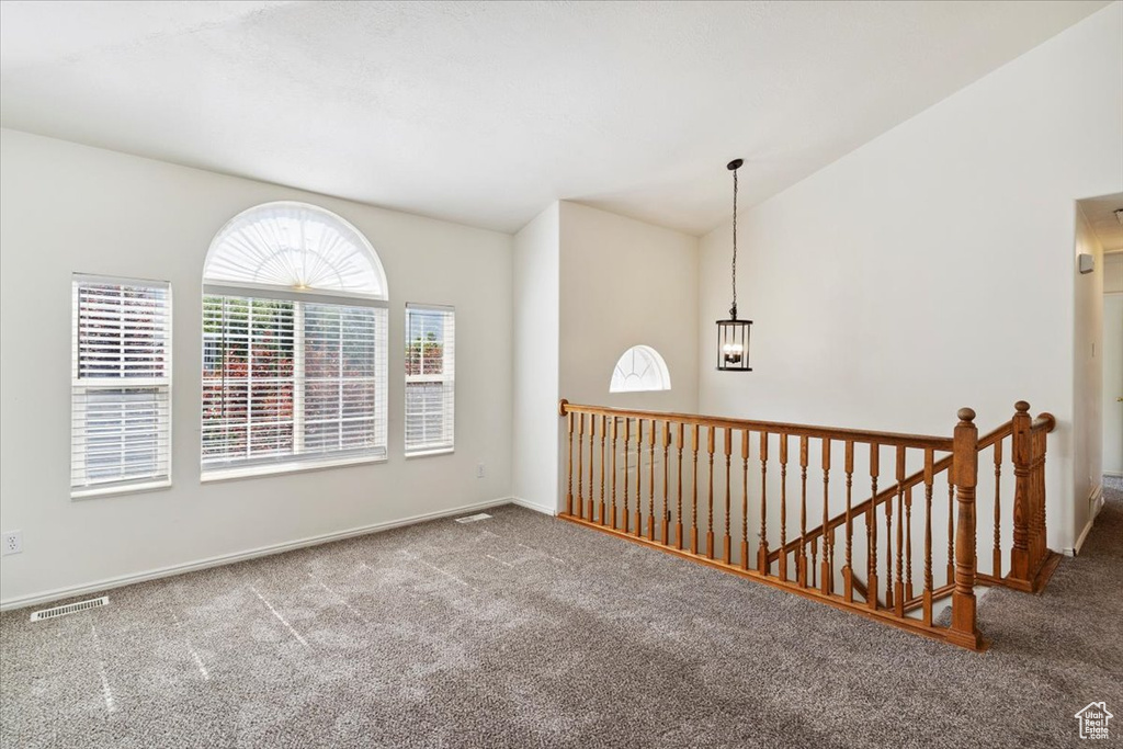 Spare room with carpet flooring, lofted ceiling, and a chandelier