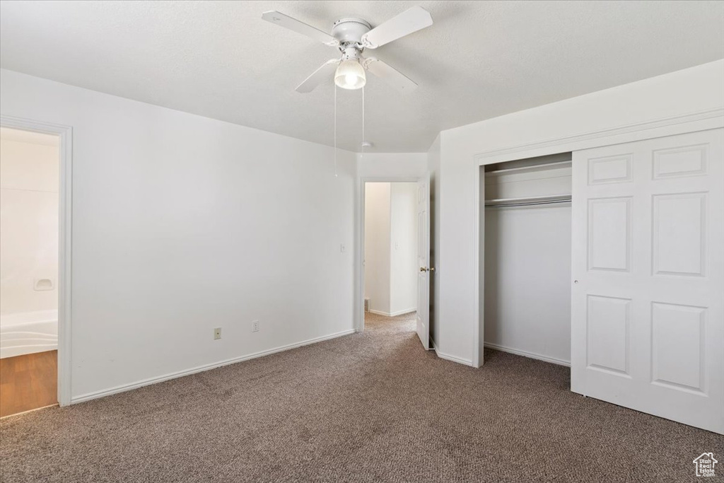 Unfurnished bedroom with carpet, a closet, ceiling fan, and ensuite bathroom