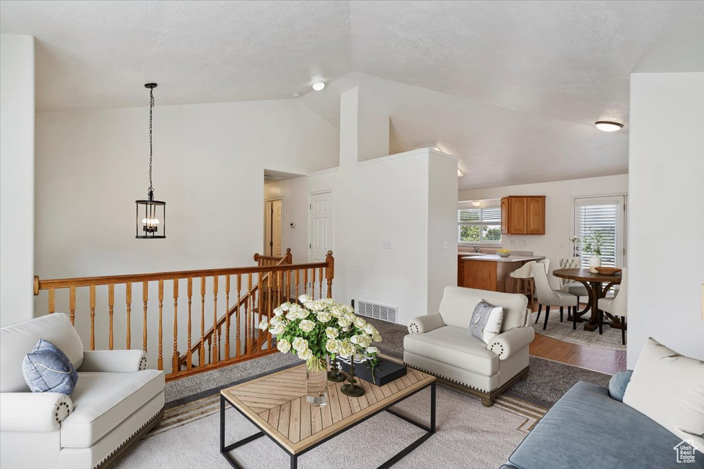 Living area featuring vaulted ceiling, a chandelier, and light wood-style flooring