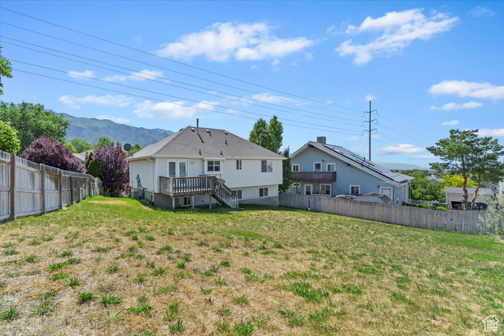 Back of property with a deck with mountain view, a fenced backyard, and stairway