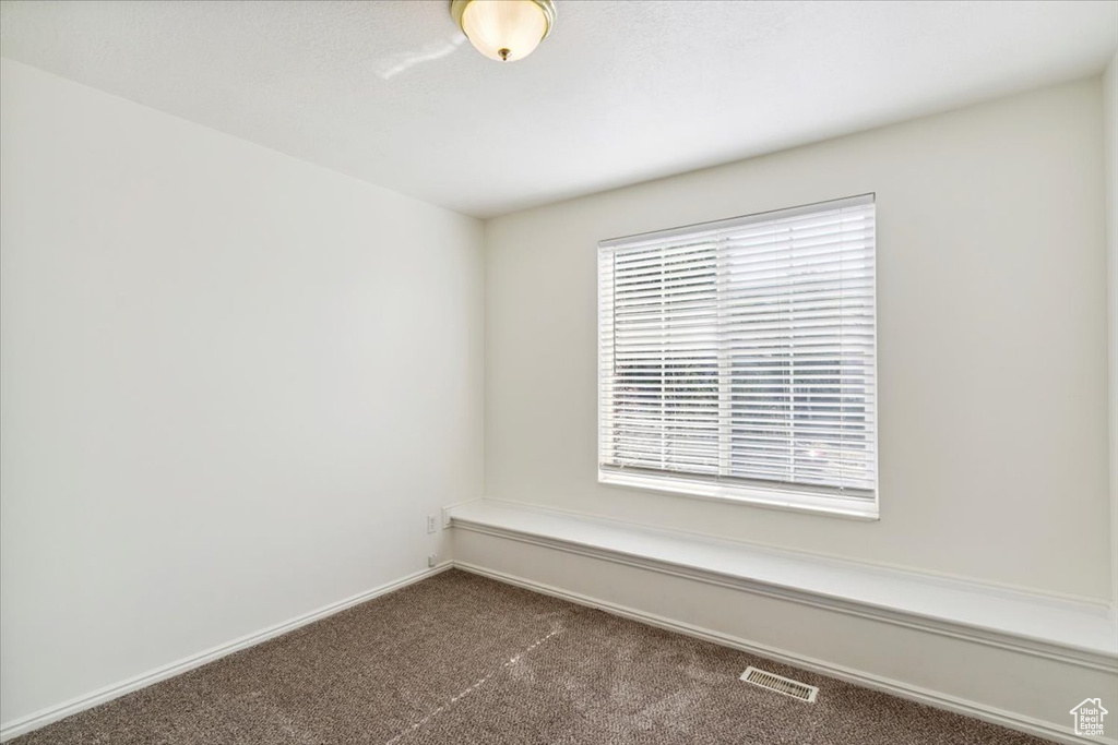 Unfurnished room featuring dark carpet and baseboards