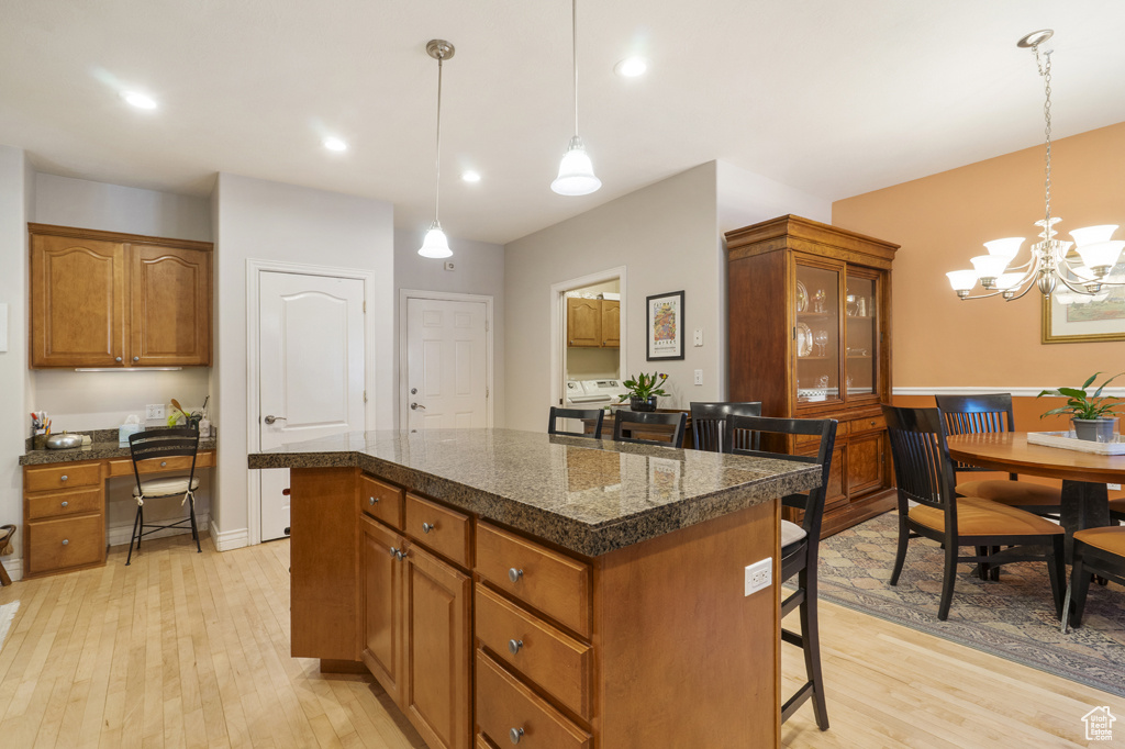 Kitchen with a breakfast bar area, light wood-type flooring, brown cabinets, a kitchen island, and recessed lighting