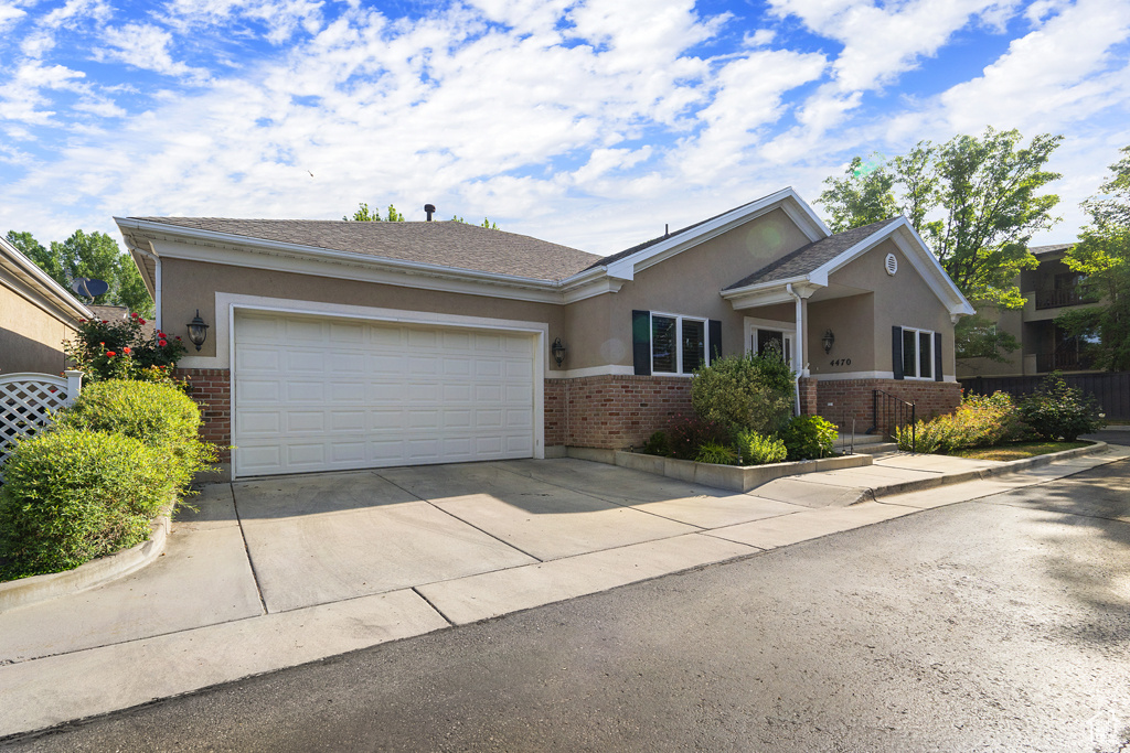 Ranch-style home featuring brick siding, stucco siding, and driveway