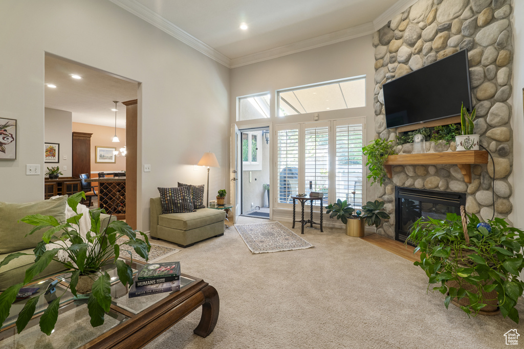 Living room featuring a stone fireplace, ornamental molding, recessed lighting, and carpet