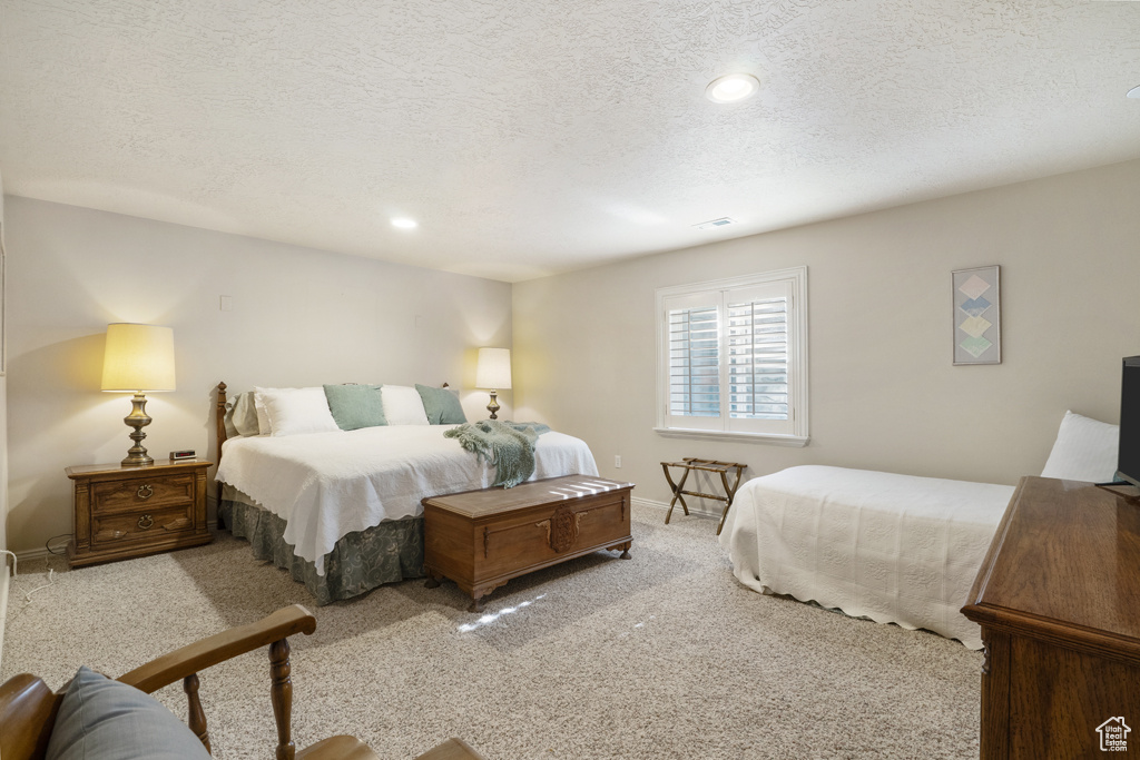 Carpeted bedroom featuring a textured ceiling and recessed lighting