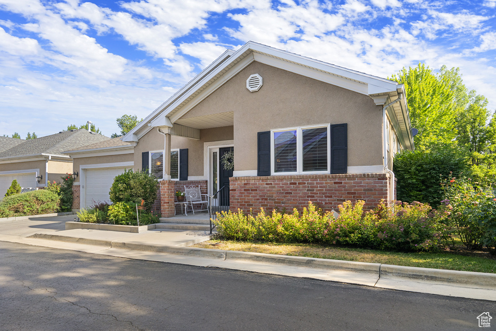 View of front of house with stucco siding, a garage, and brick siding