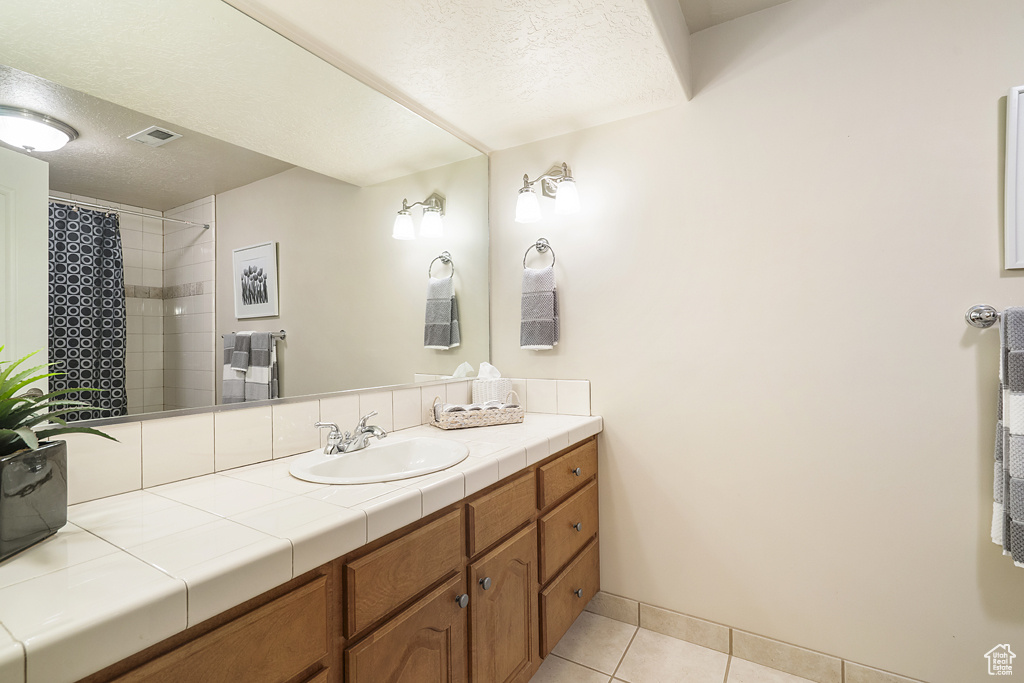 Bathroom featuring tile patterned flooring, a textured ceiling, vanity, and a shower with shower curtain