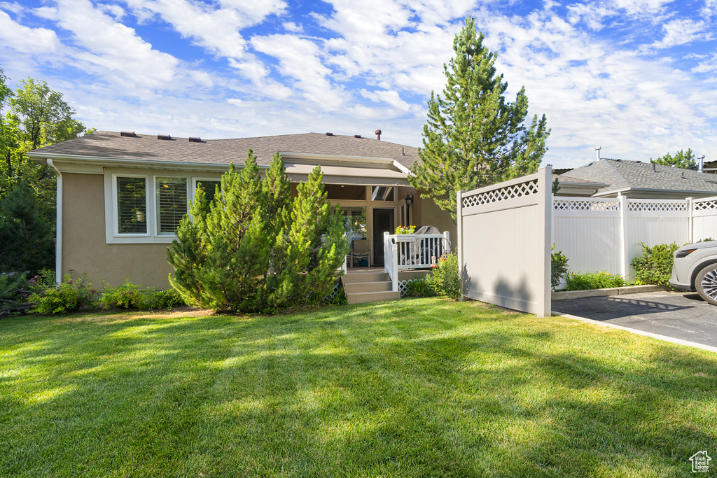 Back of property featuring uncovered parking, a deck, and stucco siding