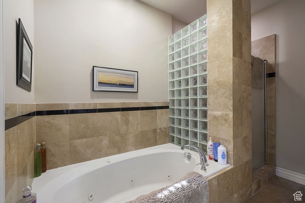 Bathroom with a tub with jets, a tile shower, and tile patterned floors