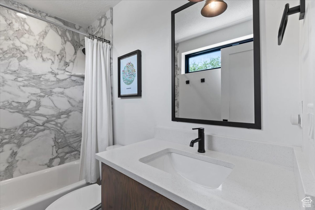 Full bathroom featuring vanity, shower / bath combination with curtain, and a textured ceiling