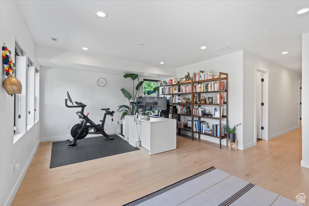 Exercise area with light wood-type flooring and recessed lighting