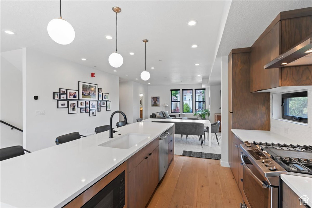 Kitchen featuring stainless steel appliances, light wood finished floors, light countertops, recessed lighting, and open floor plan