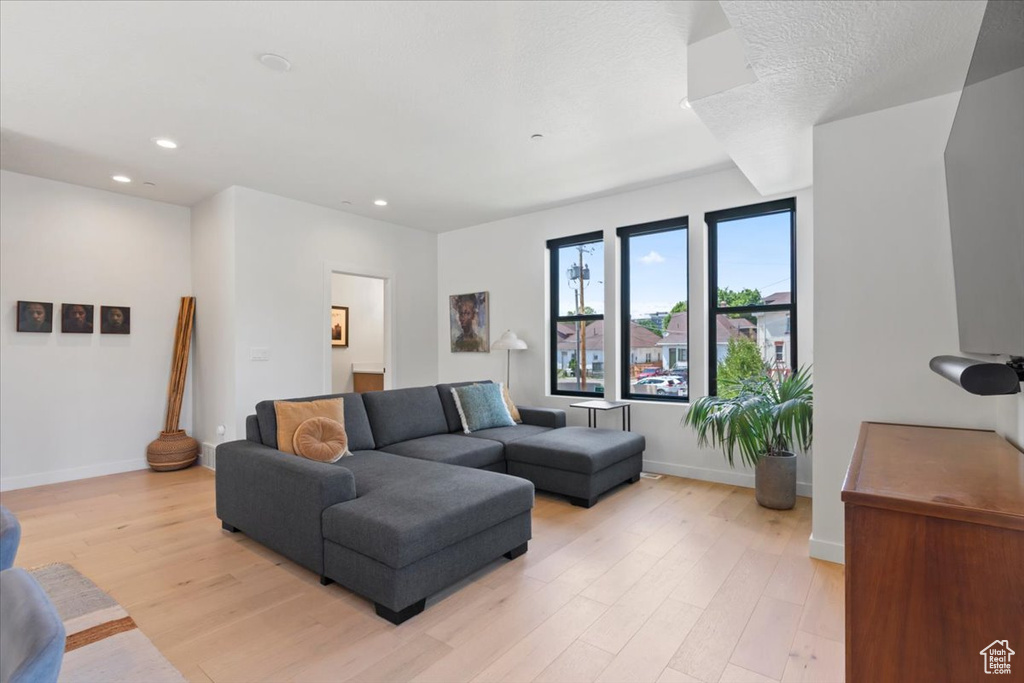 Living area with light wood finished floors and recessed lighting