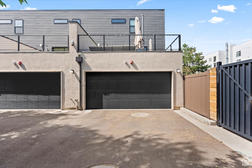 Rear view of property featuring stucco siding, an attached garage, and a balcony