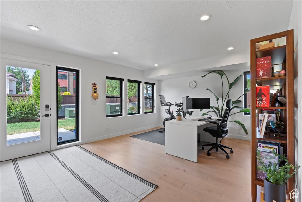 Office with light wood finished floors and recessed lighting