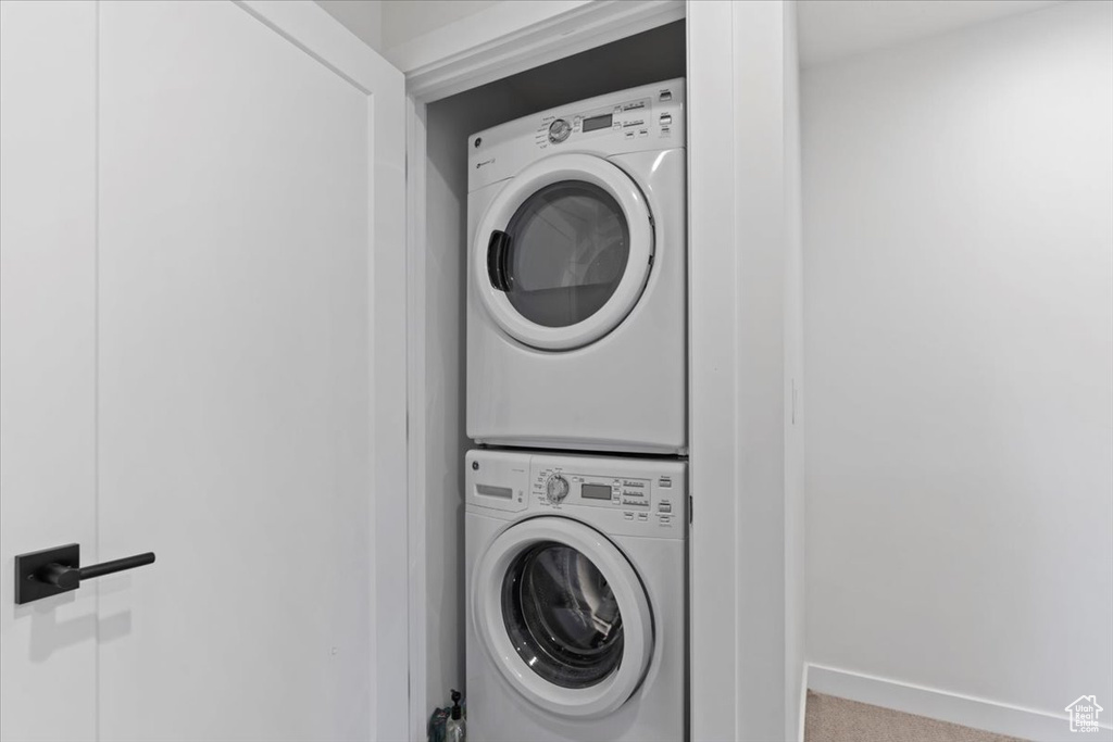Laundry room with estacked washer and dryer and carpet