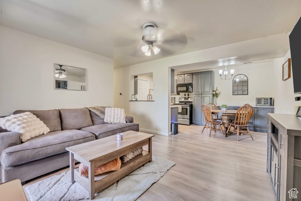 Living room with a ceiling fan, a chandelier, and light wood-style flooring