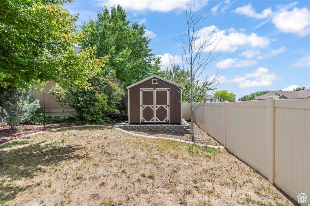 Fenced backyard featuring a storage unit
