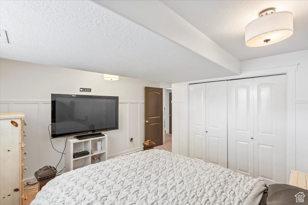 Bedroom featuring a decorative wall, a closet, and wainscoting