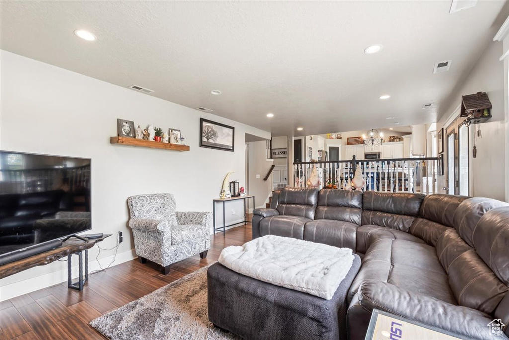 Living area with dark wood finished floors, recessed lighting, and stairs