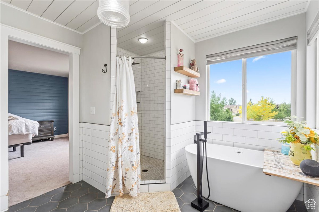 Full bath featuring a tile shower, tile patterned flooring, a freestanding bath, tile walls, and ornamental molding