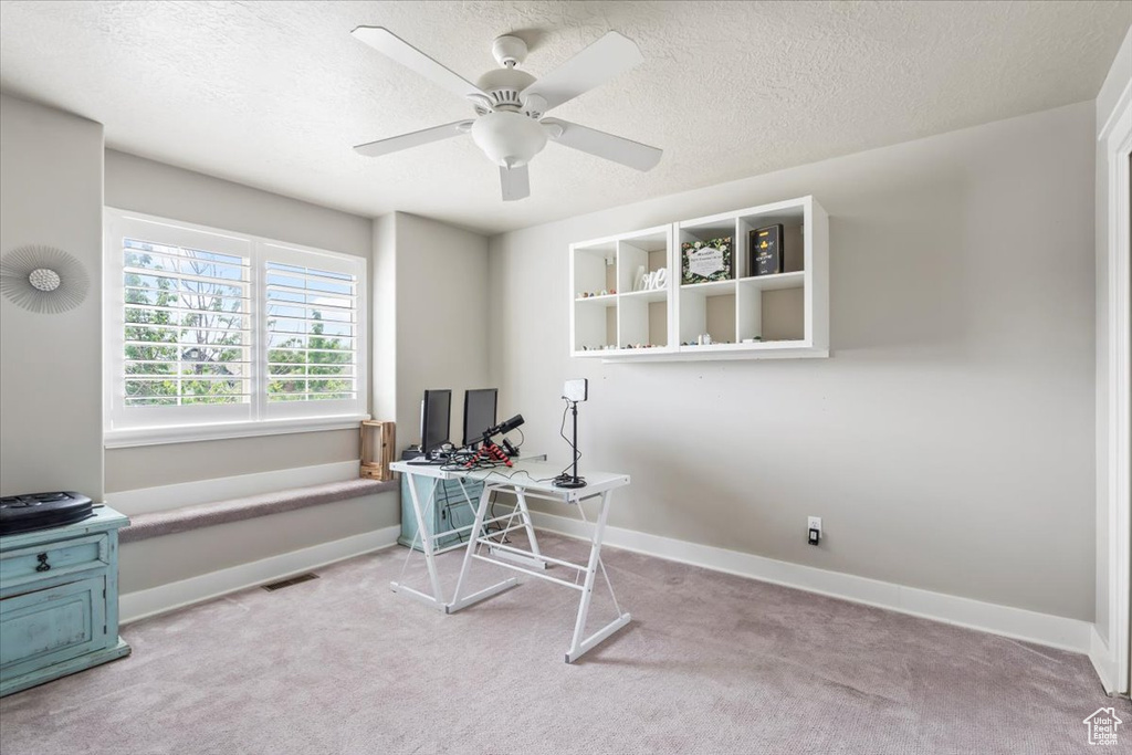 Carpeted office with a ceiling fan and a textured ceiling