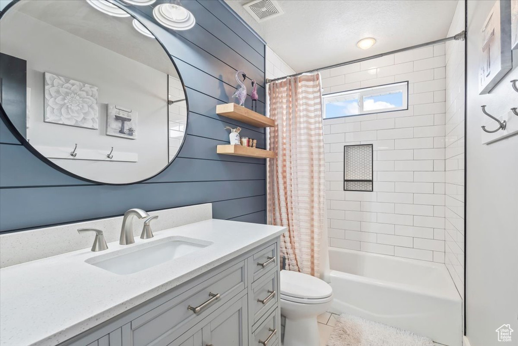 Bathroom featuring vanity, shower / tub combo with curtain, and tile patterned flooring