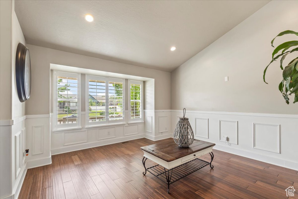 Living area with a wainscoted wall, lofted ceiling, wood finished floors, recessed lighting, and a decorative wall
