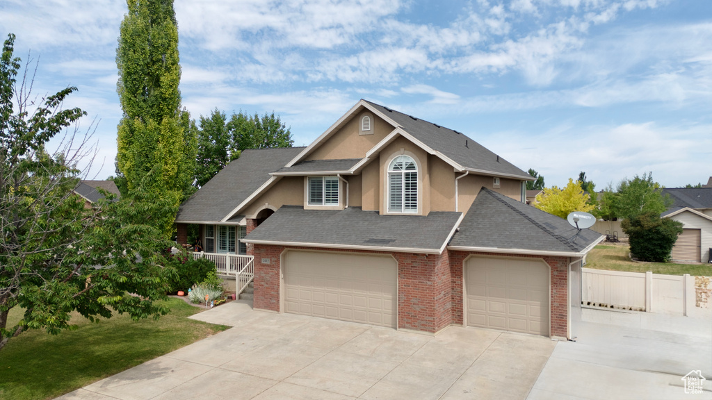 View of front of house with concrete driveway, stucco siding, brick siding, and roof with shingles
