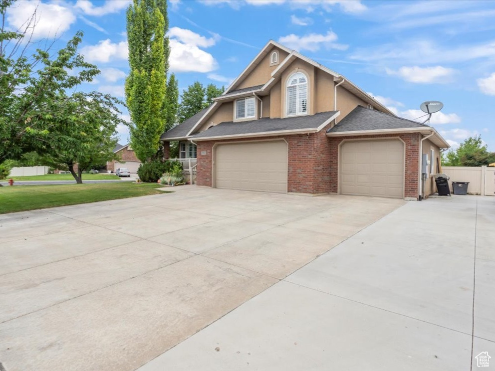 View of front of house with driveway, brick siding, stucco siding, and a garage