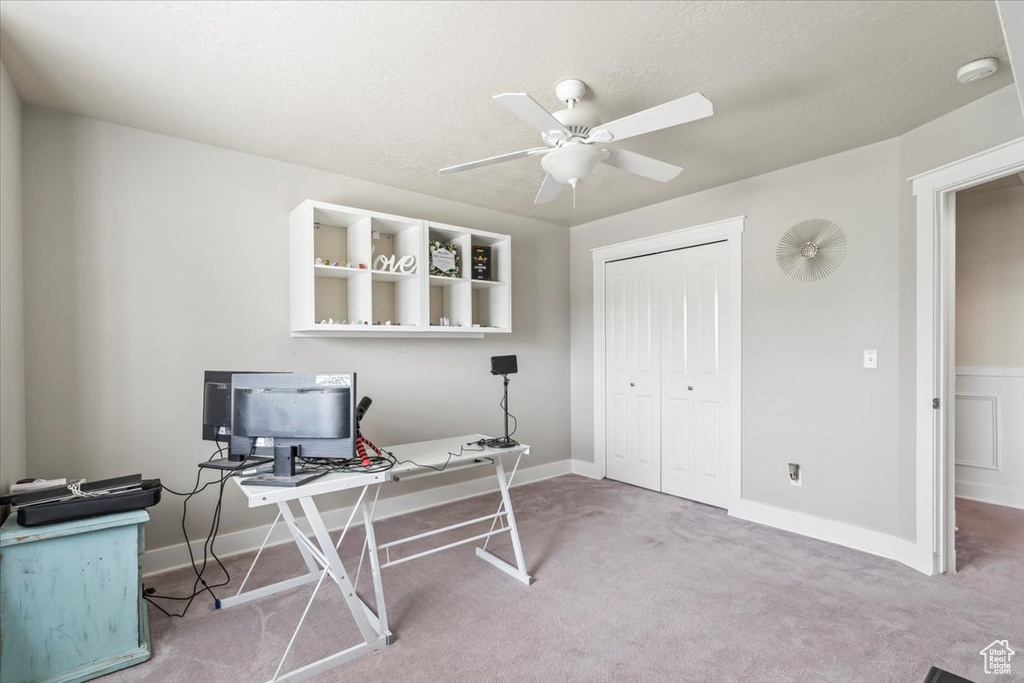Carpeted home office featuring a ceiling fan and baseboards