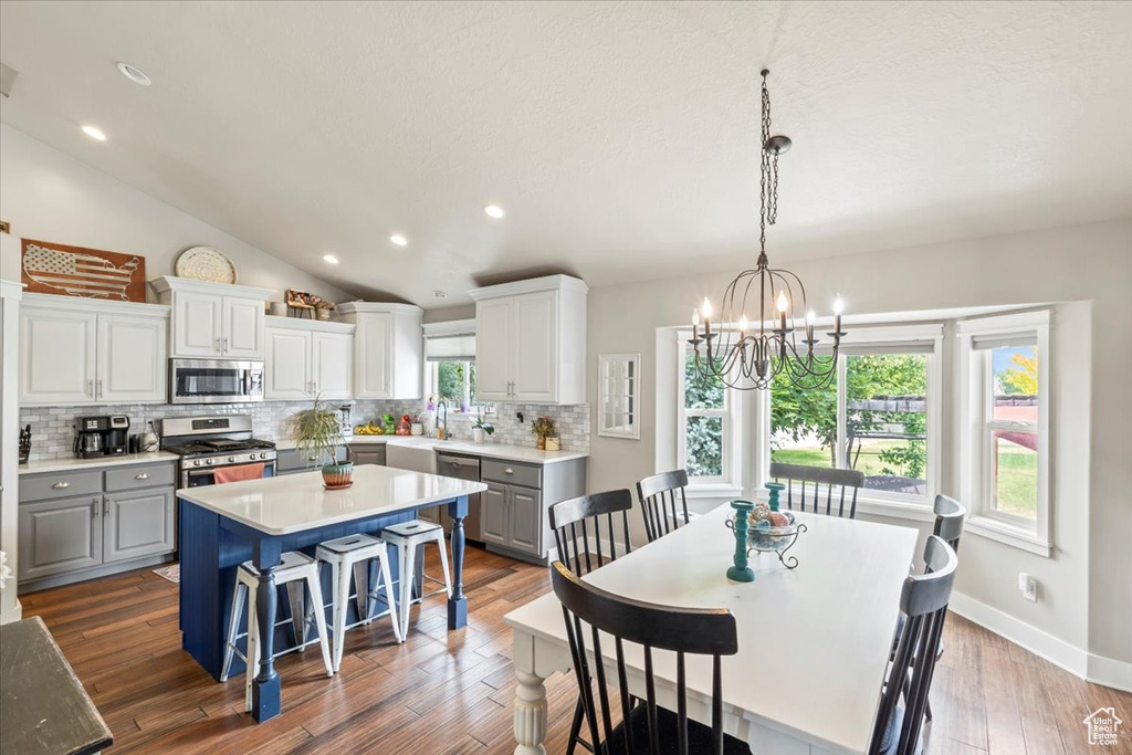 Dining space with a chandelier, wood finished floors, recessed lighting, and vaulted ceiling