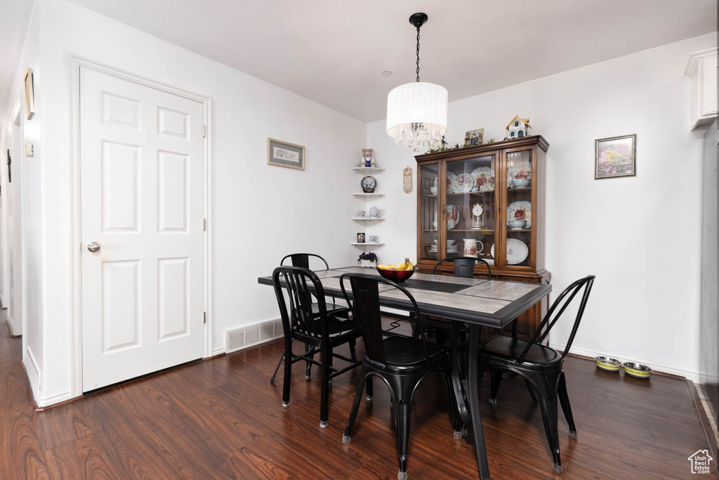 Dining room with dark wood-style floors and a chandelier