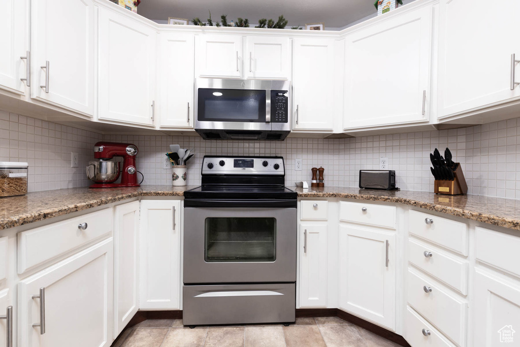 Kitchen with appliances with stainless steel finishes, decorative backsplash, and white cabinetry