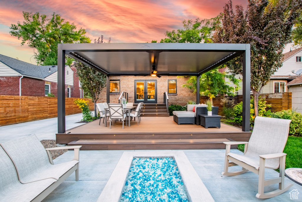Back of house featuring french doors, a deck, brick siding, an outdoor living space, and outdoor dining area